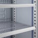 A close-up view of the interior wire shelving of a commercial glass door merchandiser refrigerator.