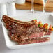 A Warrington Farm Meats bone-in ribeye steak on a white plate with a fork and knife.