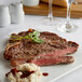 A Warrington Farm Meats porterhouse steak on a plate with mashed potatoes and a sprig of herb.