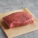 A piece of Warrington Farm Meats raw frozen sirloin steak on a piece of paper.