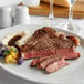 A Warrington Farm Meats T-Bone steak on a white plate with a black handle.