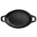 A black oval cast iron casserole dish with two handles.