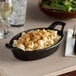 A black oval cast iron casserole dish filled with food.