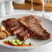 A Warrington Farm Meats frozen porterhouse steak on a plate with a fork and knife.