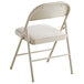 A beige folding chair with a white cushion