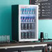 A Galaxy black countertop display refrigerator full of energy drinks in cans.