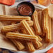 A plate of J & J Snack Foods mini churros with chocolate sauce on a table.