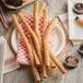 J & J Snacks Tio Pepe's California 16" King Size Churros on a plate with red and white checkered napkins and cups of chocolate.