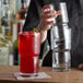 A bartender pouring a red drink into a Libbey Newton stackable beverage glass.