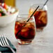 Two customizable Libbey stackable beverage glasses with ice tea on a table with a bowl of salad.