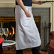 A man wearing a Choice white bistro apron holding a tray of food.