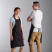 A man and woman wearing Choice black aprons standing in a professional kitchen.