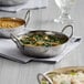 A Vollrath stainless steel bowl of food with rice and vegetables on a table.