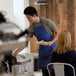 A man in a Choice royal blue apron serving food to people at a table.