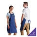 A woman wearing a royal blue Choice poly-cotton bib apron with 2 pockets.