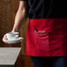 A person wearing a red Choice apron holding a cup and saucer.