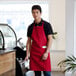 A man wearing a red Choice apron standing behind a coffee counter.