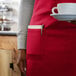 A woman wearing a red Choice apron holding a cup of coffee at a coffee shop counter.