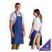 A man and woman wearing royal blue customizable aprons.