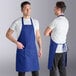 A royal blue poly-cotton standard bib apron with two front pockets, shown from the front and back.