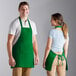 A man and woman wearing Choice Kelly Green poly-cotton bib aprons.