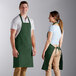A man and woman wearing Choice hunter green aprons.