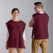 A man and woman wearing burgundy cobbler aprons.