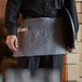 A person wearing a Choice grey standard waist apron holding a tray.