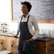 A woman wearing a black Choice front of house apron with three pockets.