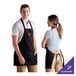 A man and woman wearing black Choice customizable aprons.