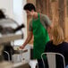 A man wearing a Choice Kelly Green bib apron serving food.