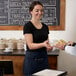 A woman in a black shirt using a navy blue Choice poly-cotton apron to serve food to a man.