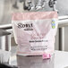 A silver tub of 90 Noble Chemical water soluble detergent packets on a school kitchen counter.