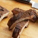 Pieces of meat seasoned with Regal Big Flavor BBQ Seasoning on a cutting board next to a knife.