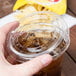 A hand holding a Solo plastic cup with a drink and a clear plastic lid with a straw slot.