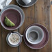 A table with Libbey Matte Mulberry porcelain plates and bowls on it.