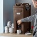 A man using a CaterGator insulated beverage dispenser to fill a coffee machine with a white mug.