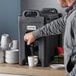 A man pouring coffee into a CaterGator insulated beverage dispenser.