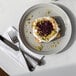 A Libbey Englewood porcelain plate with a piece of bread with cream cheese and fruit toppings on it.