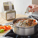 A person pouring Regal Delicious Stew Herb Blend into a pot of soup.