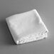 A folded white Intedge rectangular cloth table cover on a gray surface.