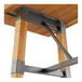 A Lancaster Table & Seating trestle table base with honey maple finish and metal legs on a wooden table.