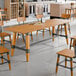 A Lancaster Table & Seating industrial honey maple finish trestle table base for a large table.