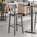 A Lancaster Table & Seating industrial bar stool with a slate gray metal base and wooden seat.