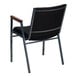 A black chair with wooden armrests and grey dots on the fabric.