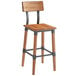 A Lancaster Table & Seating Rustic Industrial bar height chair with a wooden seat and backrest and metal legs.