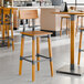 A Lancaster Table & Seating industrial bar stool with a honey maple finish and a metal frame and back.