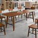 A Lancaster Table & Seating trestle table base with a wooden top on it.
