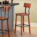 A Lancaster Table & Seating Industrial Bar Stool with Rustic Mahogany Finish next to a counter.