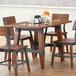 A Lancaster Table & Seating solid wood dining table with chairs and wine glasses on it.